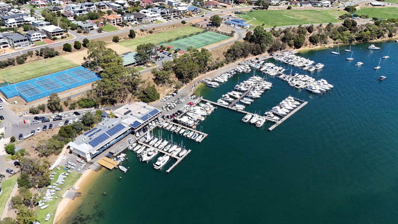 Stunning aerial view of Bicton Yacht Club and marina in Bicton, Western Australia, showcasing moored boats and surrounding sports facilities.